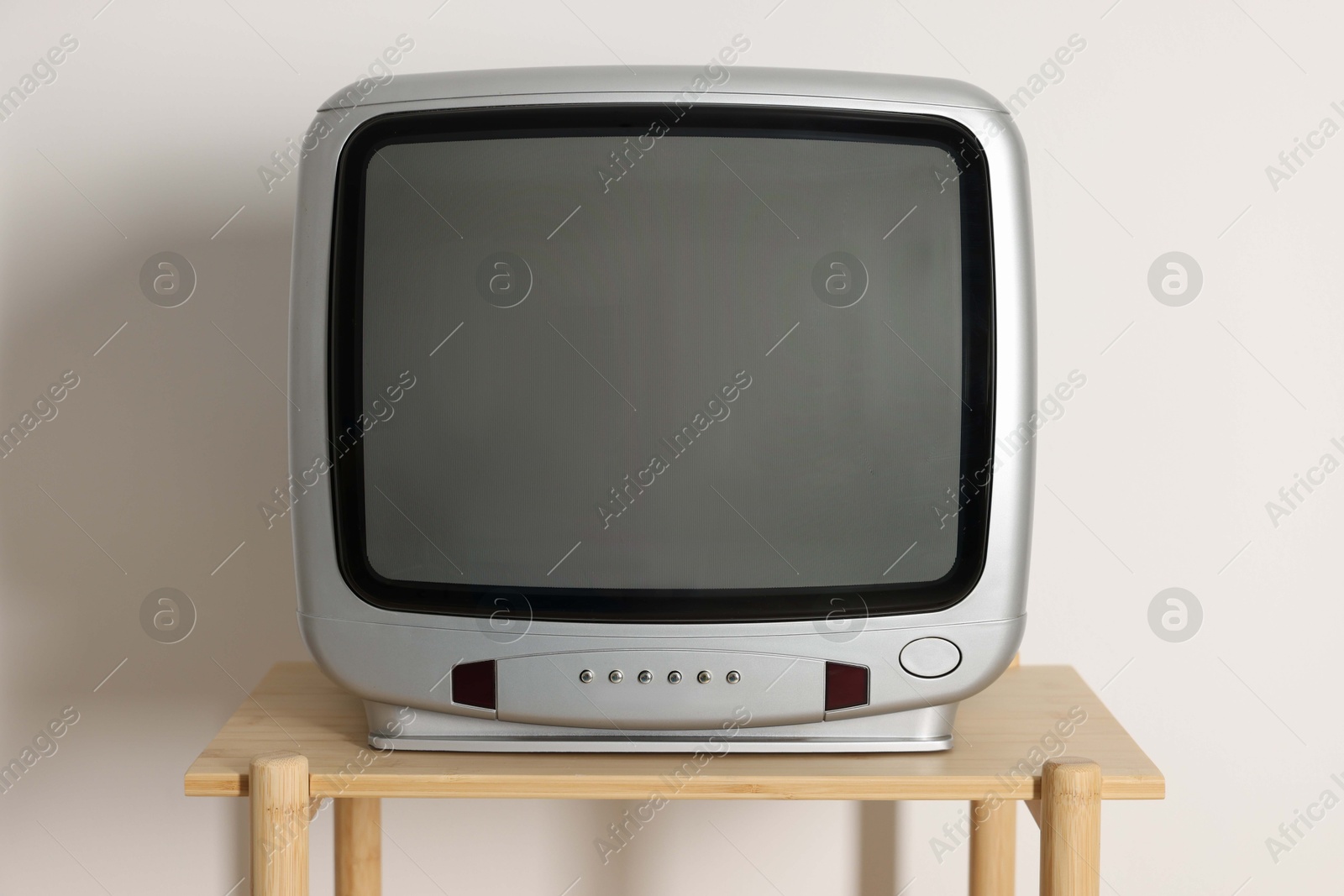 Photo of Retro tv set on wooden shelf against white wall