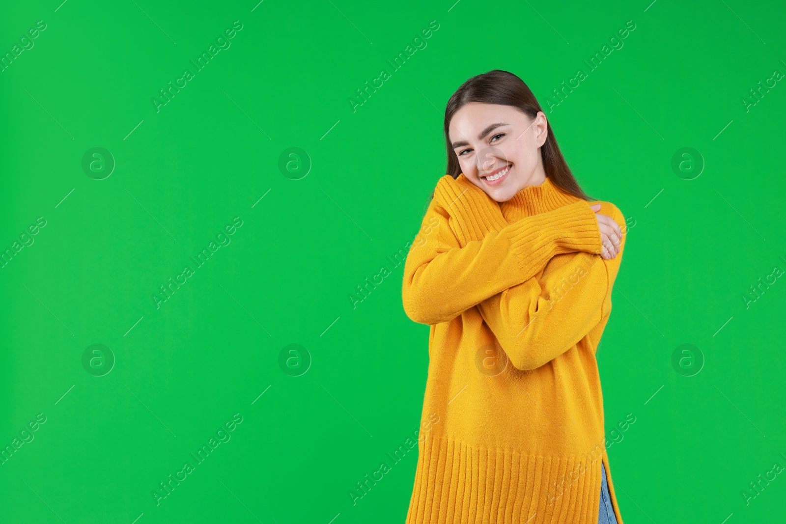 Photo of Charming young woman hugging herself on green background. Space for text