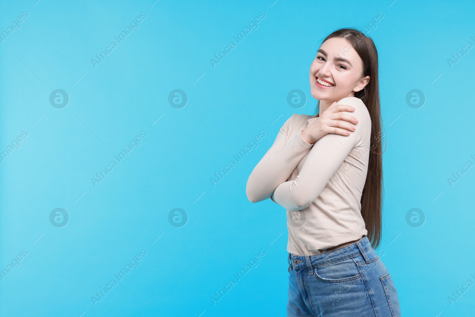 Photo of Charming young woman hugging herself on light blue background. Space for text