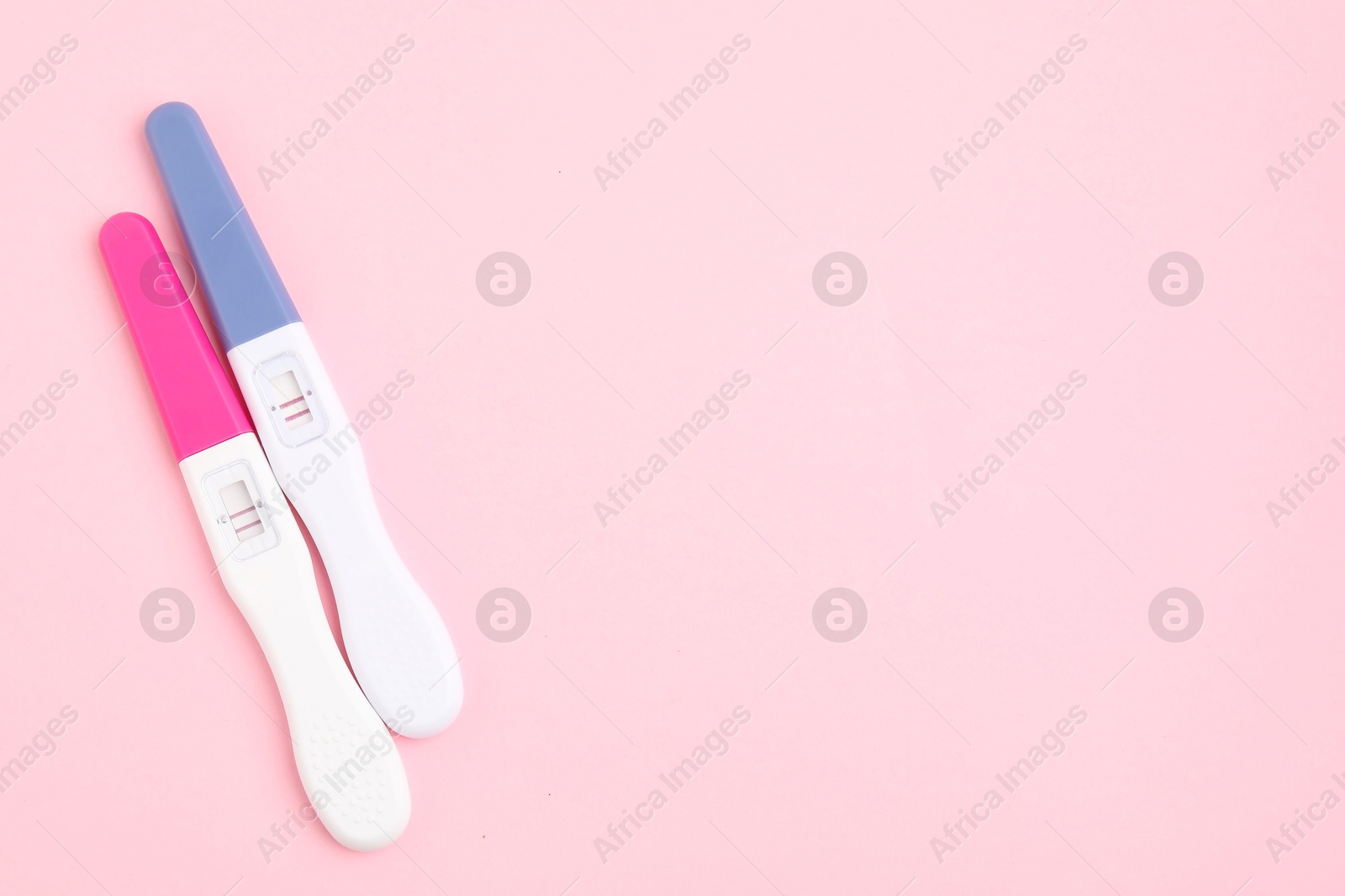 Photo of Pregnancy tests on pink background, above view. Space for text