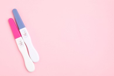 Photo of Pregnancy tests on pink background, above view. Space for text