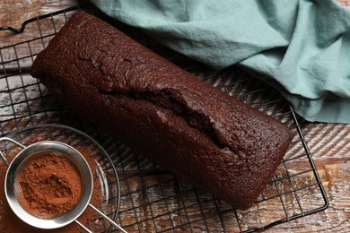 Photo of Tasty chocolate sponge cake and cocoa powder on wooden table, flat lay