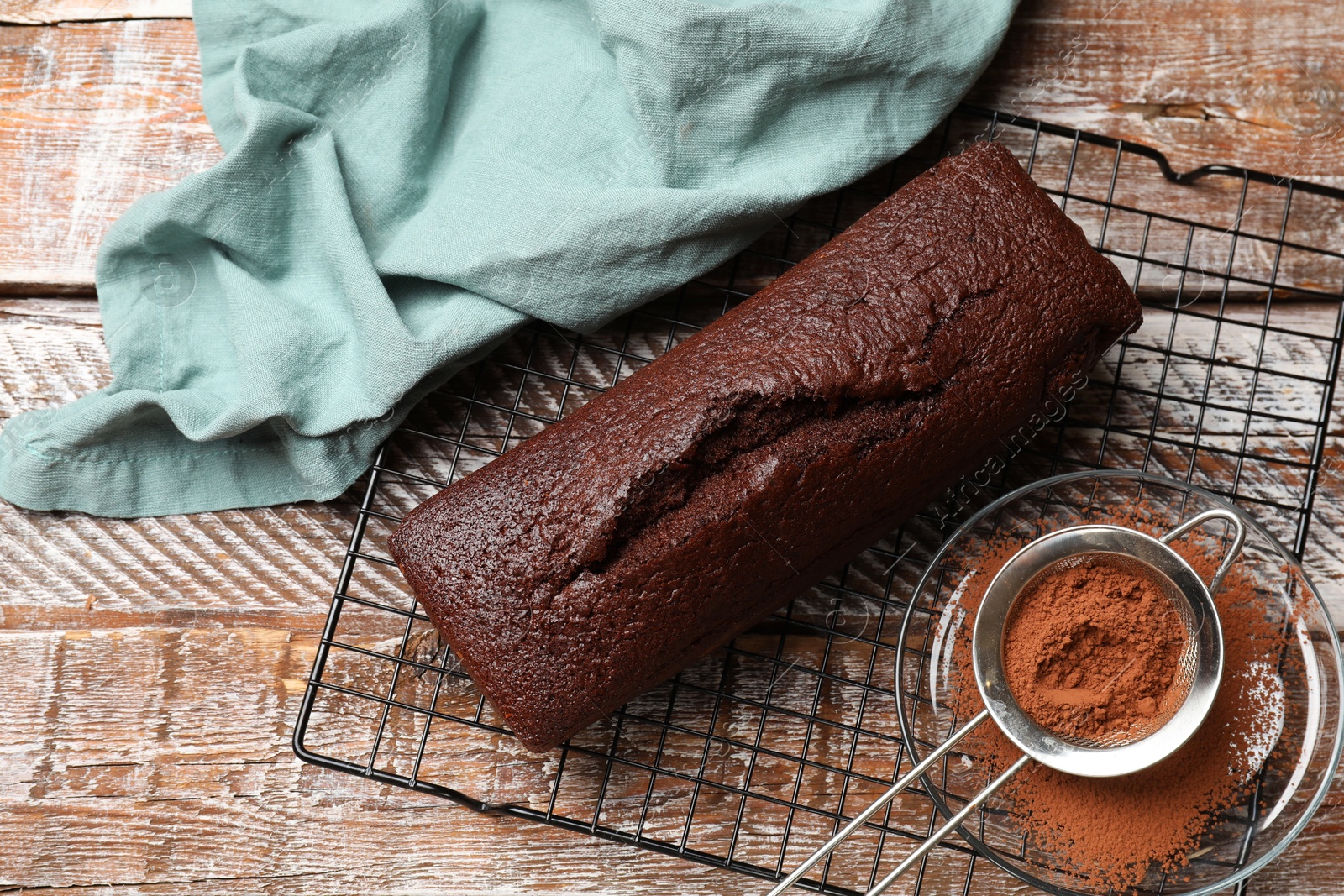 Tasty chocolate sponge cake and cocoa powder on wooden table, flat lay Photo of Tasty chocolate sponge cake and cocoa powder on wooden table, flat lay