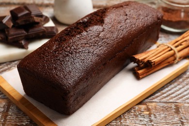 Photo of Tasty chocolate sponge cake and ingredients on wooden table, closeup