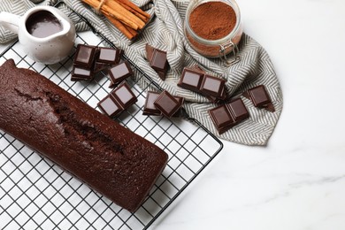 Photo of Tasty chocolate sponge cake and ingredients on white marble table, flat lay