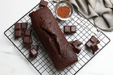 Photo of Tasty chocolate sponge cake and ingredients on white marble table, flat lay