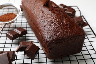 Photo of Tasty chocolate sponge cake and ingredients on white table, closeup