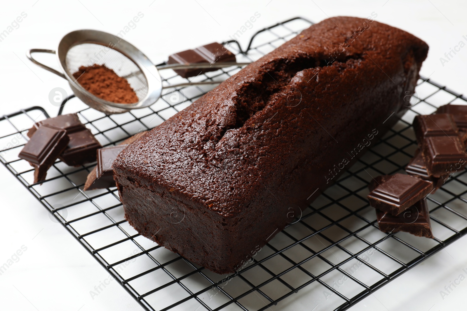 Photo of Tasty chocolate sponge cake and ingredients on white table, closeup