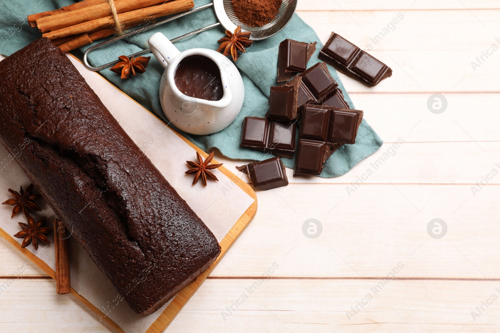 Photo of Tasty chocolate sponge cake and ingredients on white wooden table, flat lay. Space for text