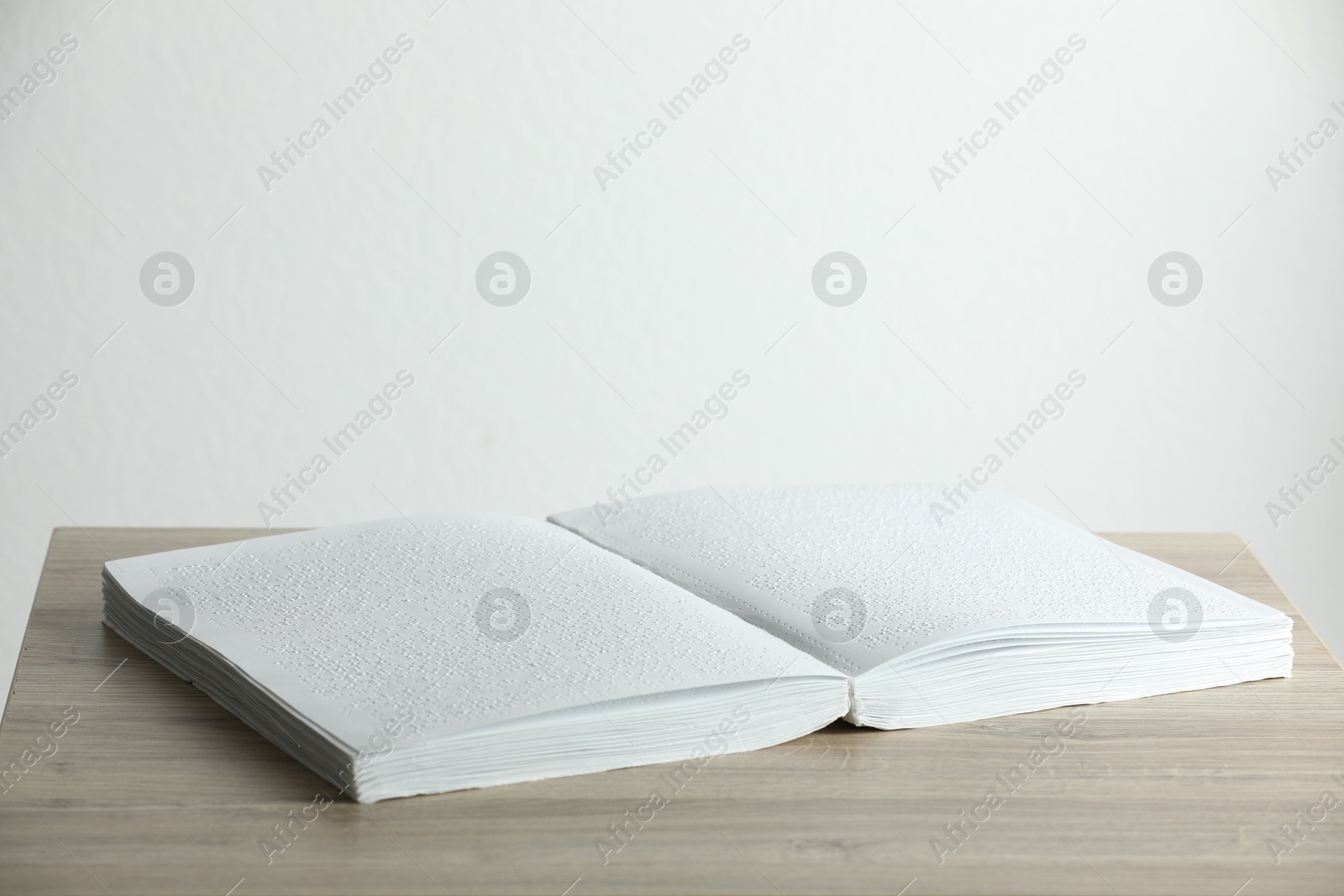 Photo of Book with Braille text on wooden table. Education and leisure for blind people