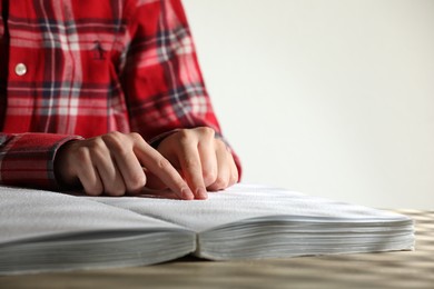 Blind woman reading book written in Braille at table, closeup