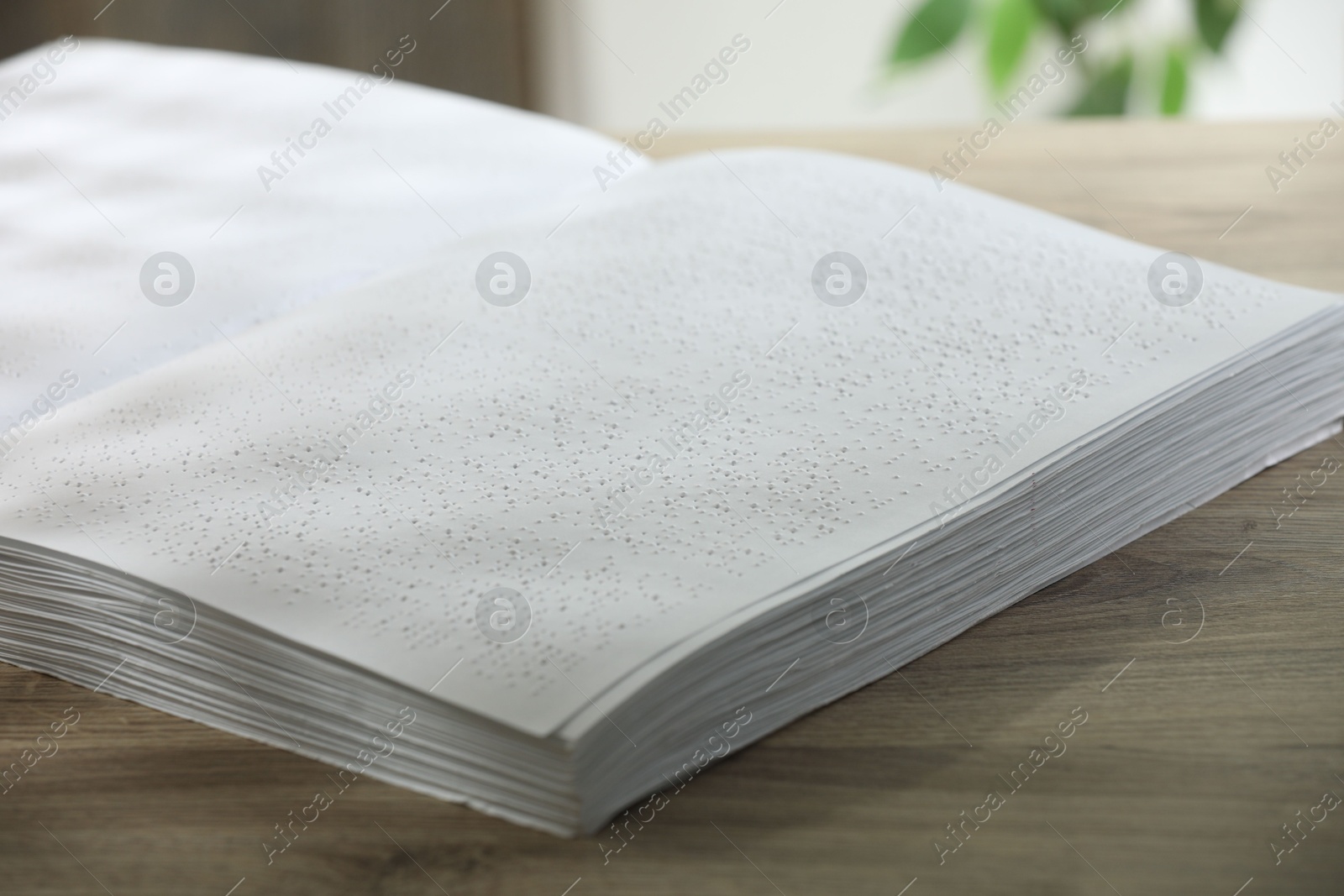 Photo of Book with Braille text on wooden table, closeup. Education and leisure for blind people