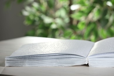 Photo of Book with Braille text on table, closeup. Education and leisure for blind people