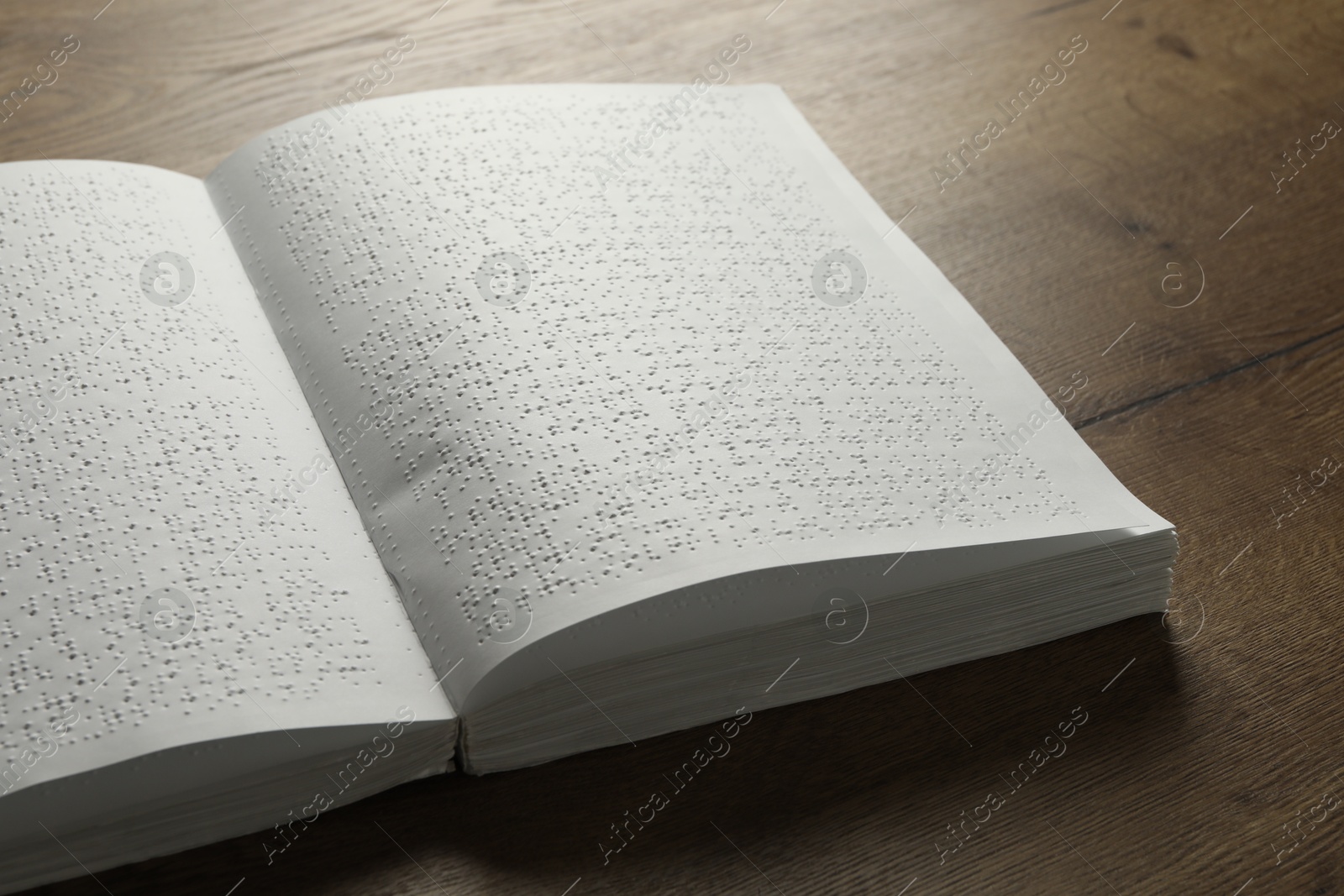 Photo of Book with Braille text on wooden table. Education and leisure for blind people