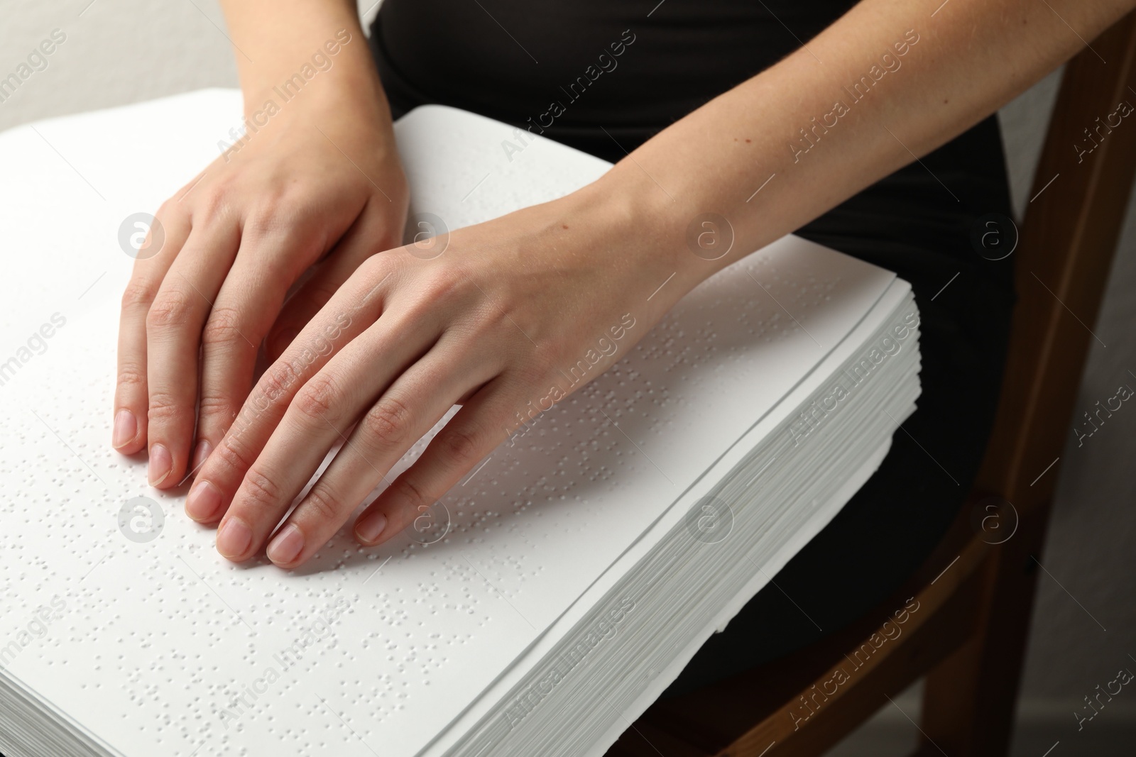 Photo of Blind woman reading book written in Braille indoors, closeup