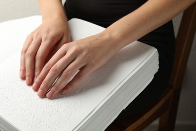 Photo of Blind woman reading book written in Braille indoors, closeup