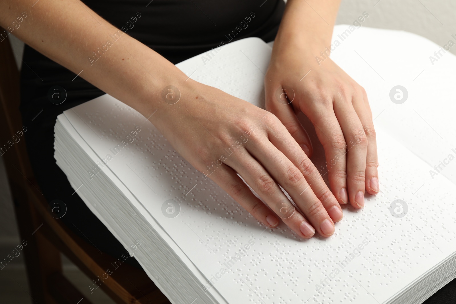 Photo of Blind woman reading book written in Braille indoors, closeup