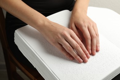 Photo of Blind woman reading book written in Braille indoors, closeup