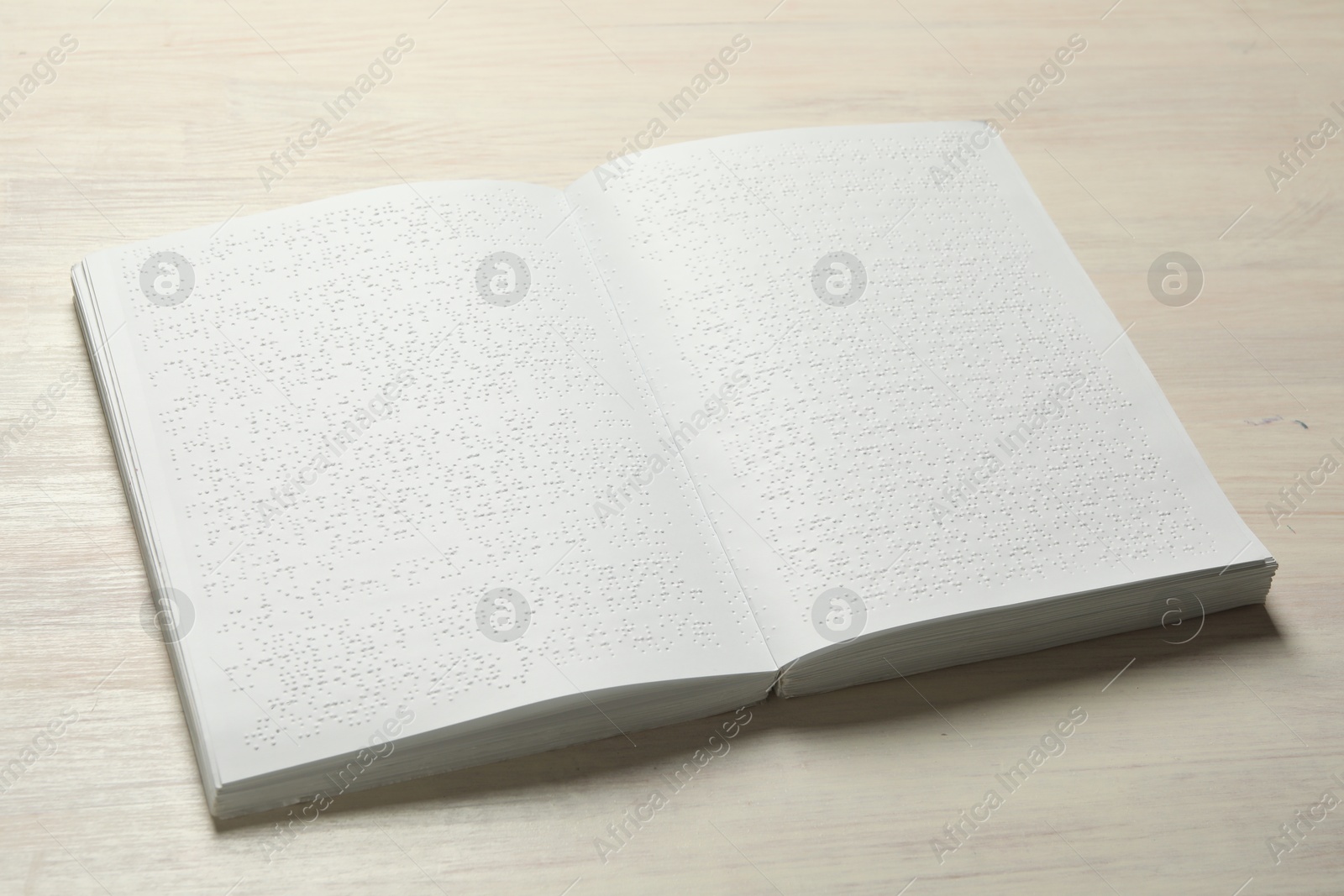 Photo of Book with Braille text on wooden table. Education and leisure for blind people