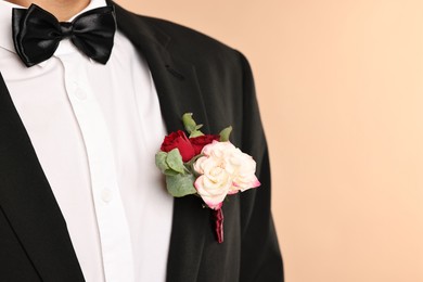 Photo of Groom in suit with stylish boutonniere on beige background, closeup. Space for text