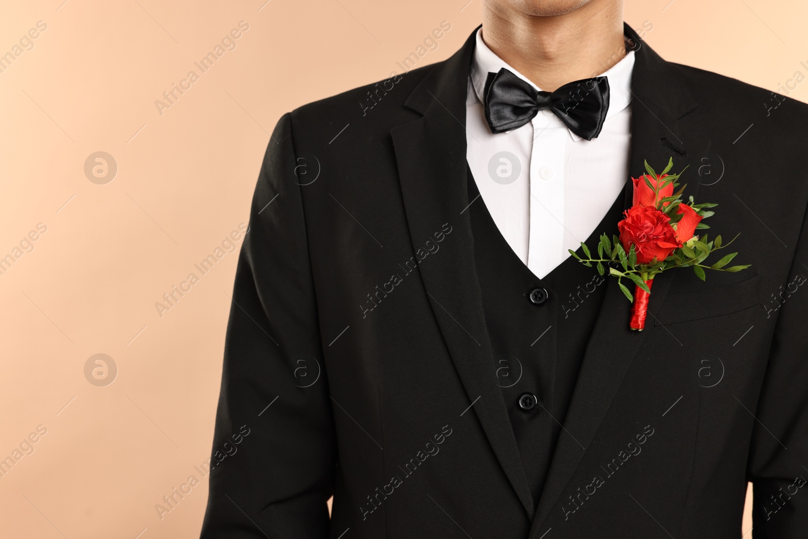 Photo of Groom in suit with stylish boutonniere on beige background, closeup