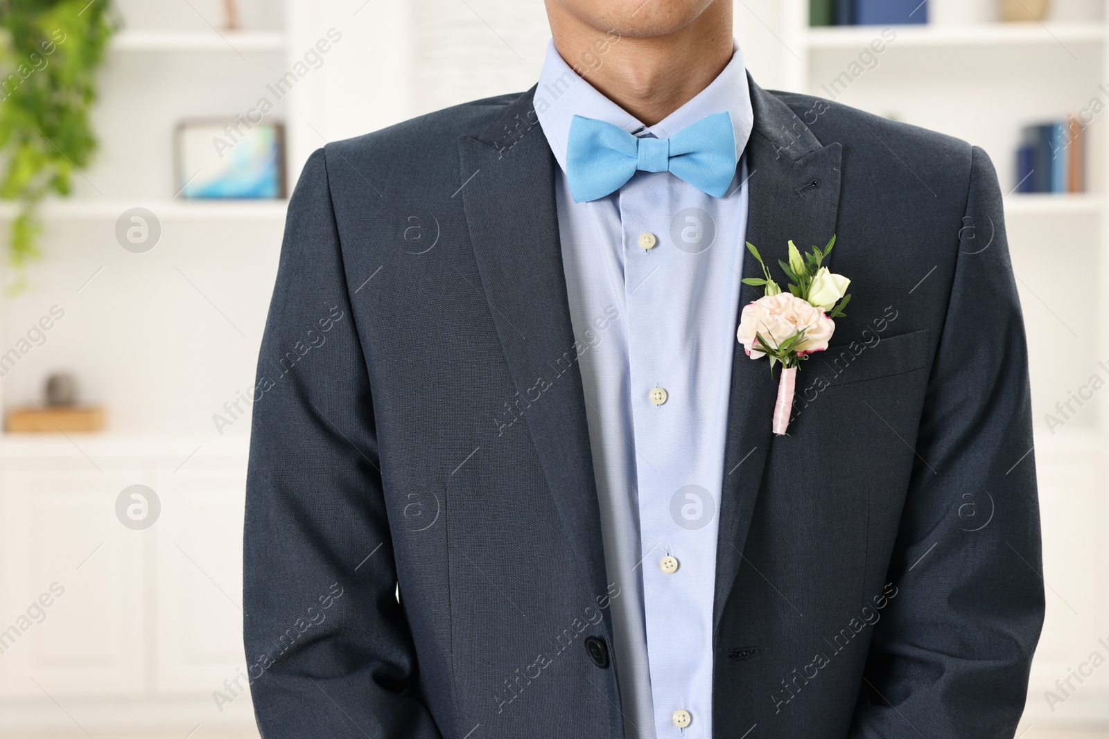 Photo of Groom in suit with stylish boutonniere indoors, closeup