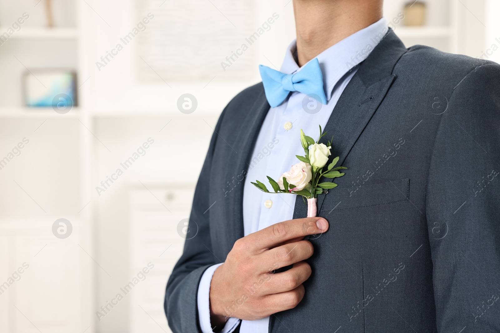 Photo of Groom in suit with stylish boutonniere indoors, closeup. Space for text