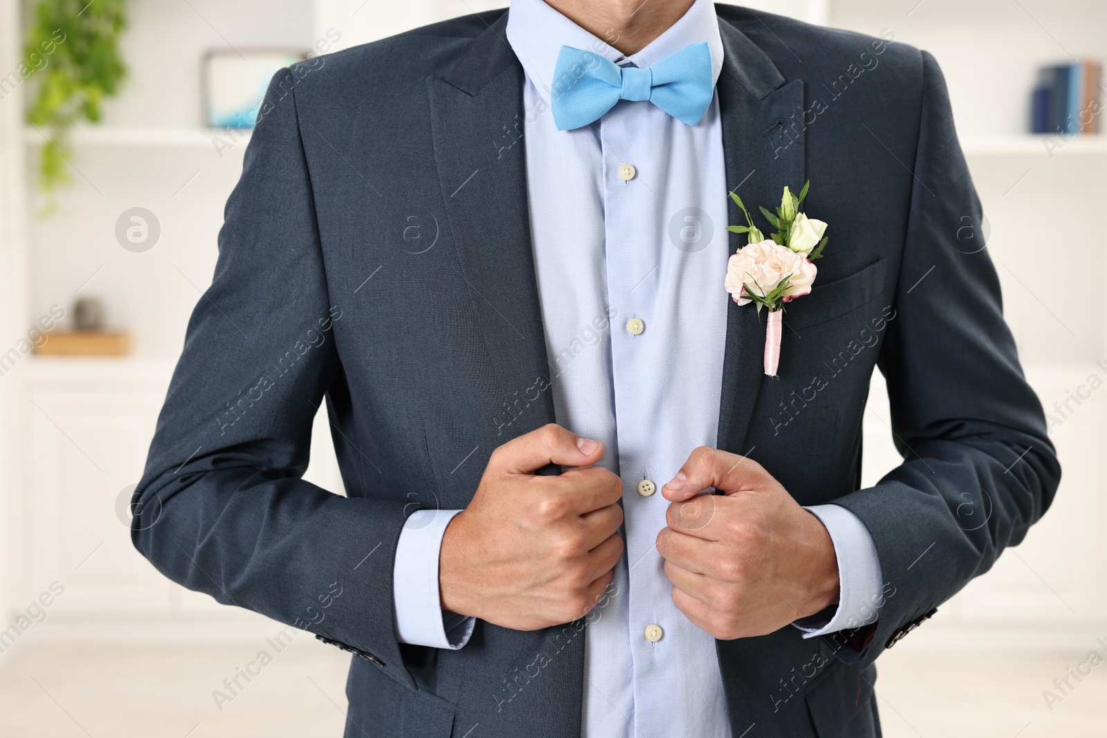 Photo of Groom in suit with stylish boutonniere indoors, closeup