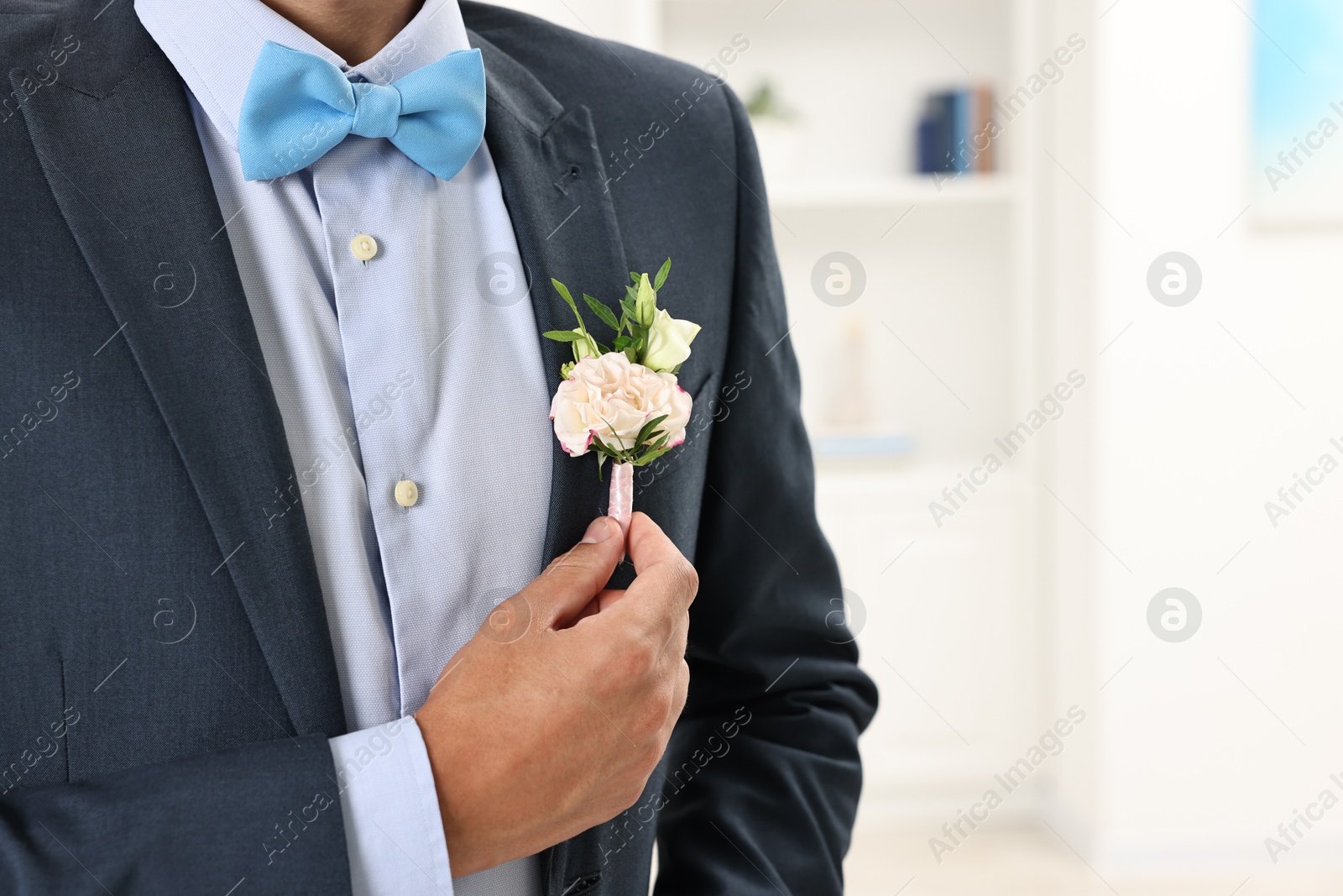 Photo of Groom in suit with stylish boutonniere indoors, closeup. Space for text