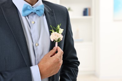 Photo of Groom in suit with stylish boutonniere indoors, closeup. Space for text