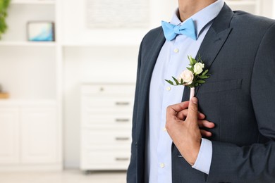 Photo of Groom in suit with stylish boutonniere indoors, closeup. Space for text