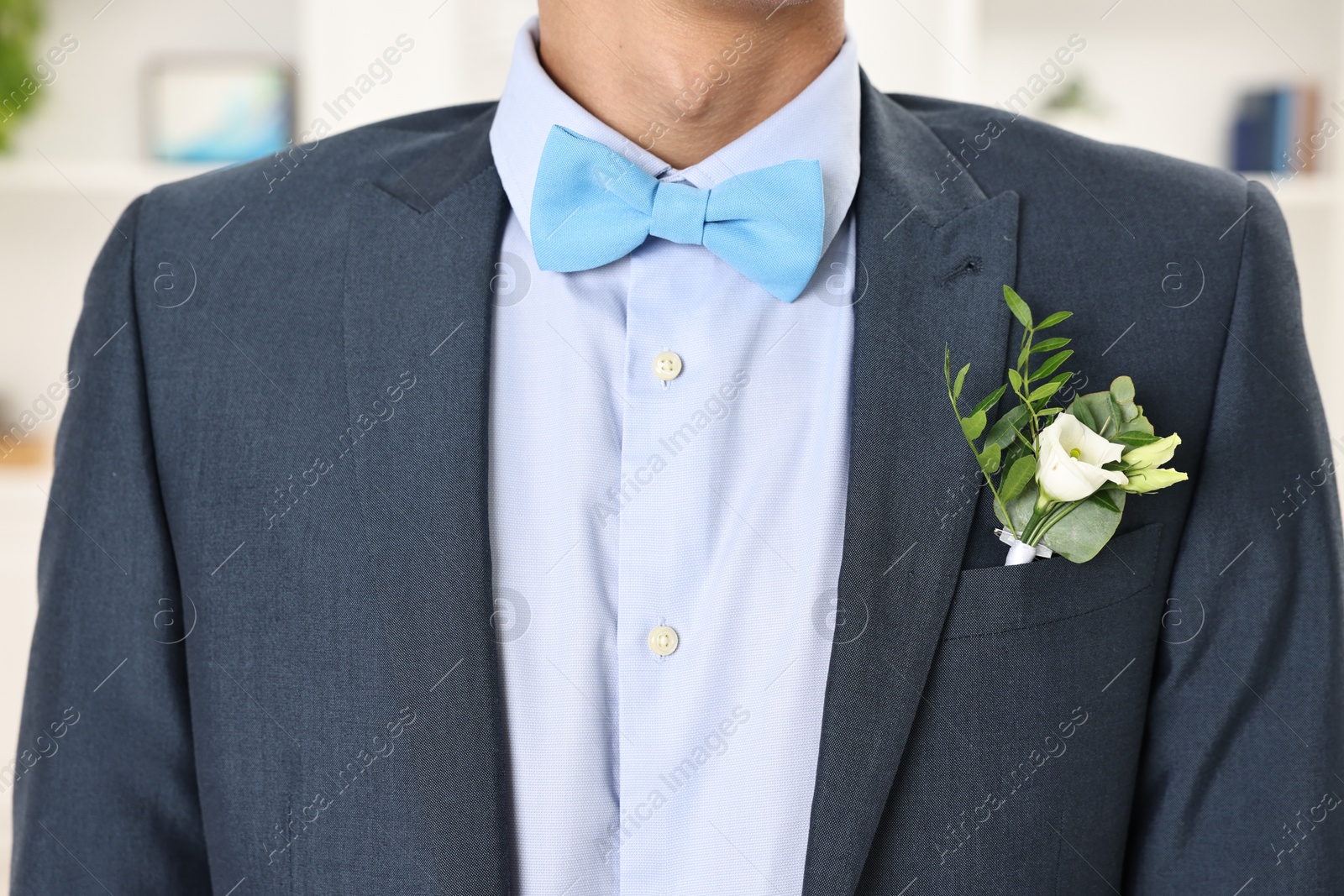 Photo of Groom in suit with stylish boutonniere indoors, closeup