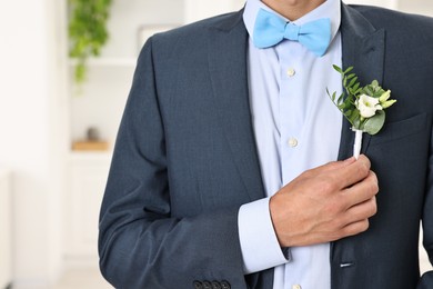 Photo of Groom in suit with stylish boutonniere indoors, closeup