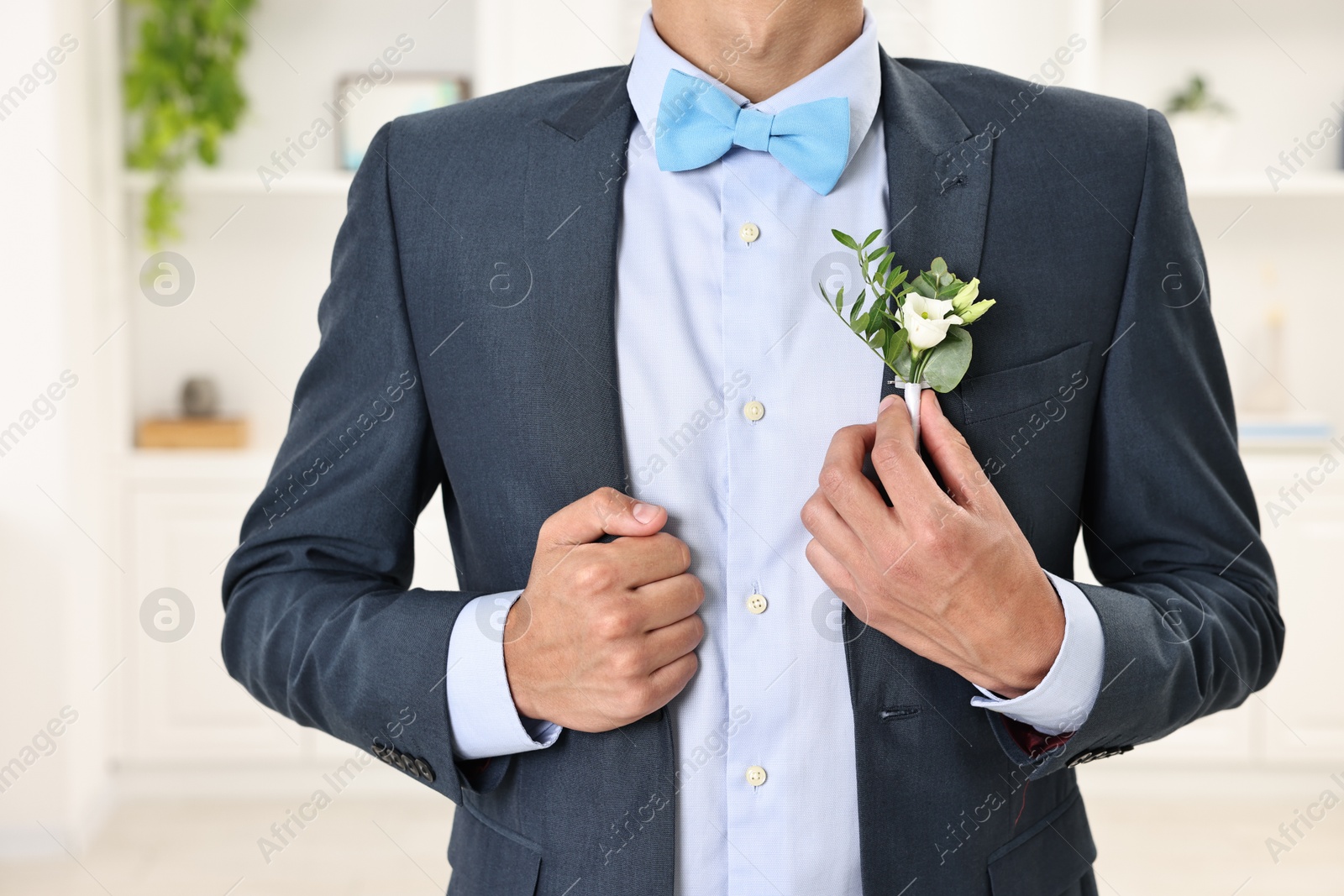 Photo of Groom in suit with stylish boutonniere indoors, closeup