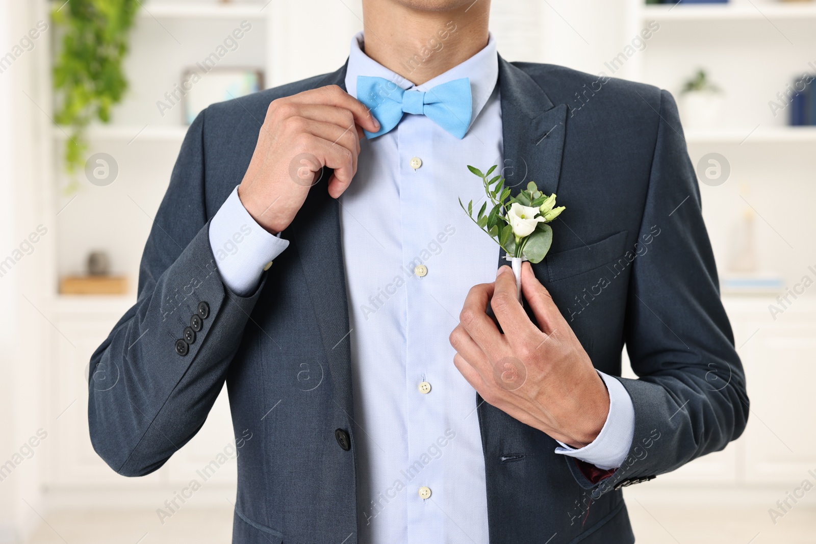 Photo of Groom in suit with stylish boutonniere indoors, closeup