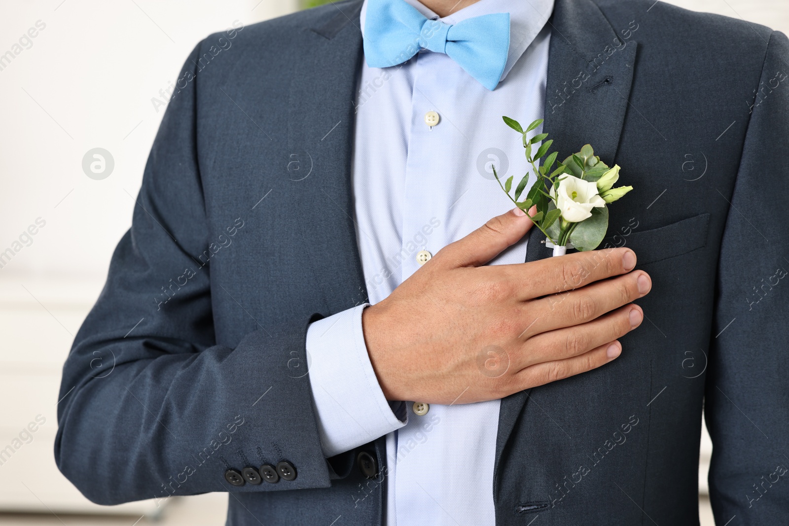 Photo of Groom in suit with stylish boutonniere indoors, closeup