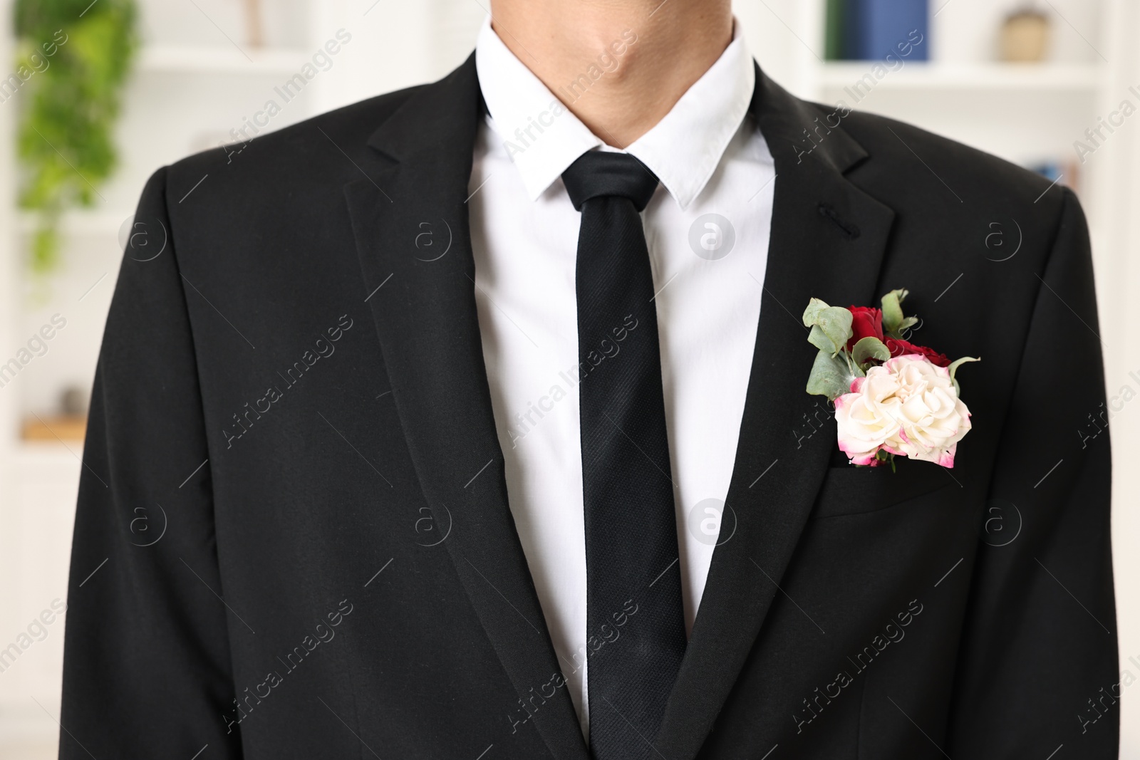 Photo of Groom in suit with stylish boutonniere indoors, closeup