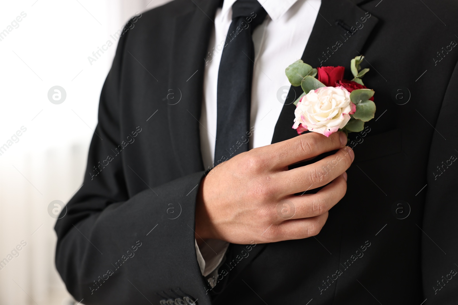 Photo of Groom in suit with stylish boutonniere indoors, closeup