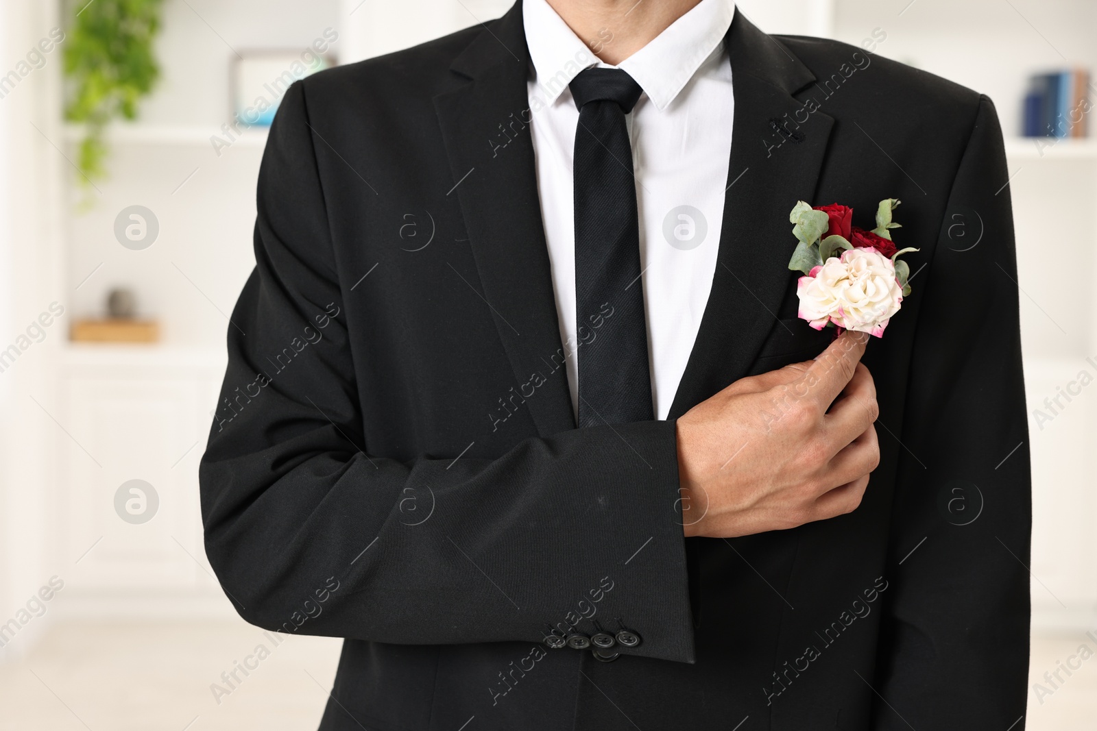 Photo of Groom in suit with stylish boutonniere indoors, closeup