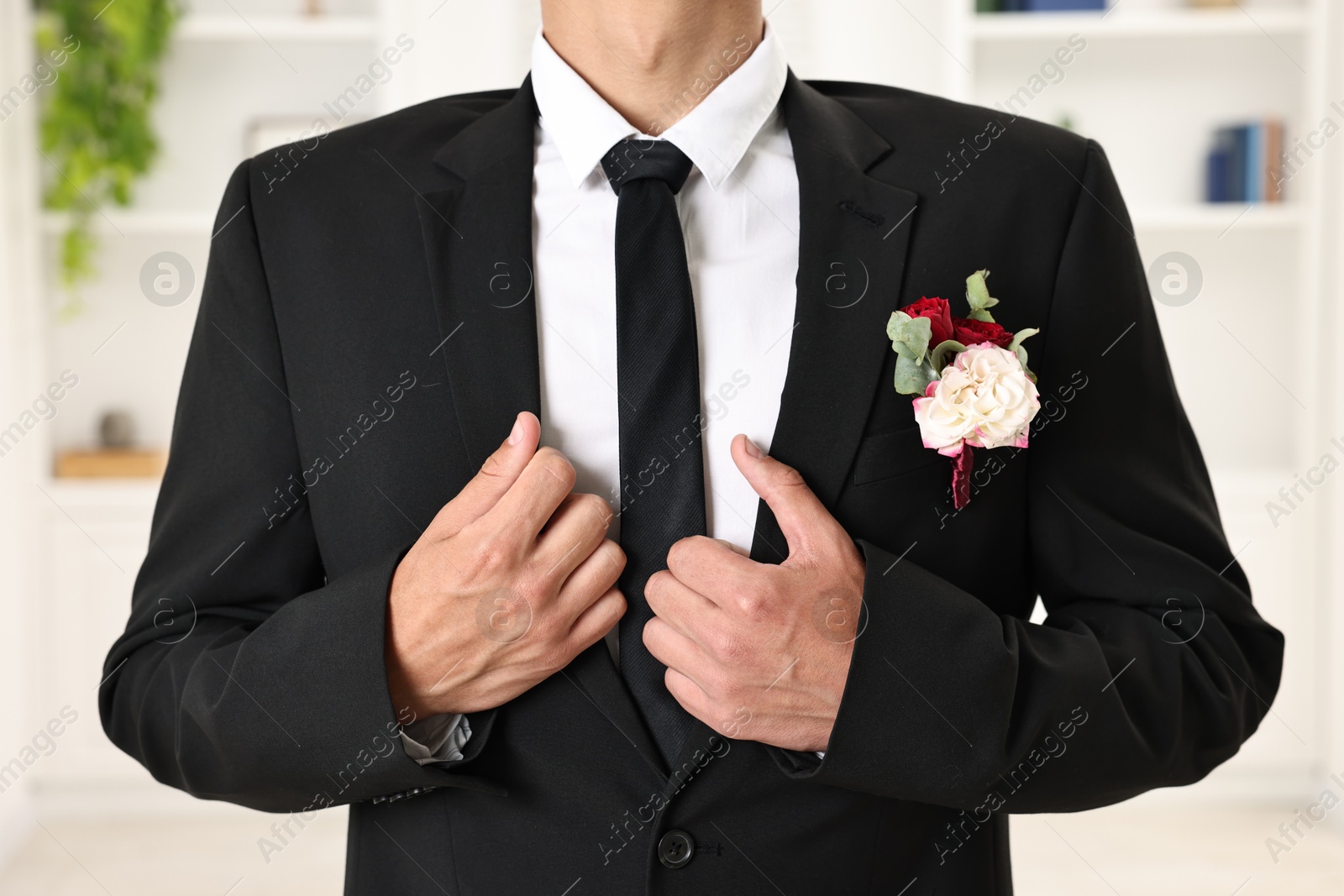 Photo of Groom in suit with stylish boutonniere indoors, closeup