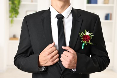 Photo of Groom in suit with stylish boutonniere indoors, closeup