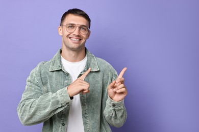 Photo of Smiling man with dental braces pointing at something on violet background. Space for text