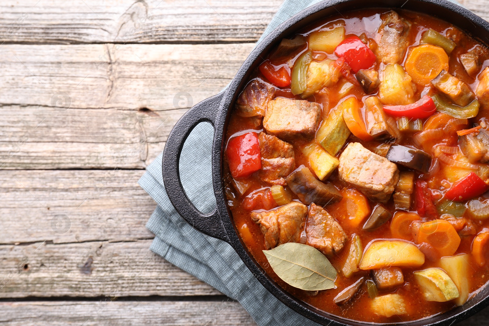 Photo of Delicious stew with vegetables in pot on wooden table, top view. Space for text