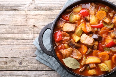 Photo of Delicious stew with vegetables in pot on wooden table, top view. Space for text