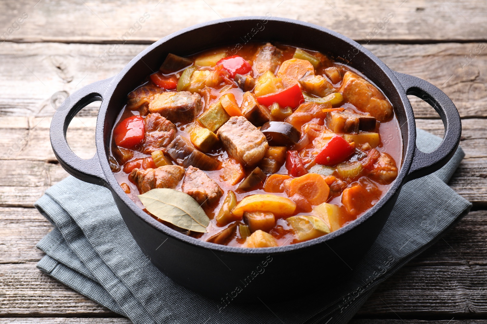 Photo of Delicious stew with vegetables in pot on wooden table, closeup