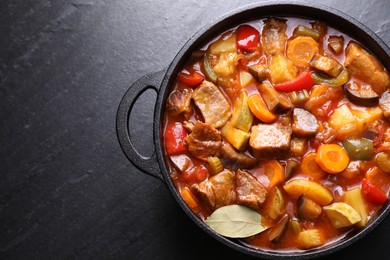 Delicious stew with vegetables in pot on gray textured table, top view. Space for text