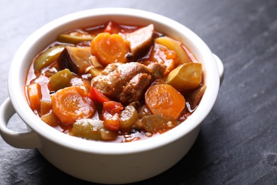 Photo of Delicious stew with vegetables in bowl on gray textured table, closeup