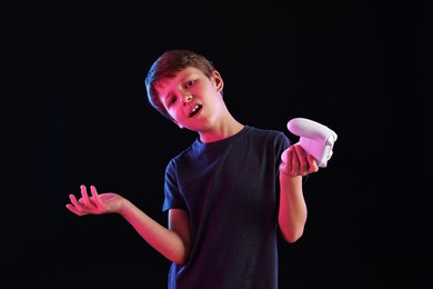 Cute little boy with controller on black background