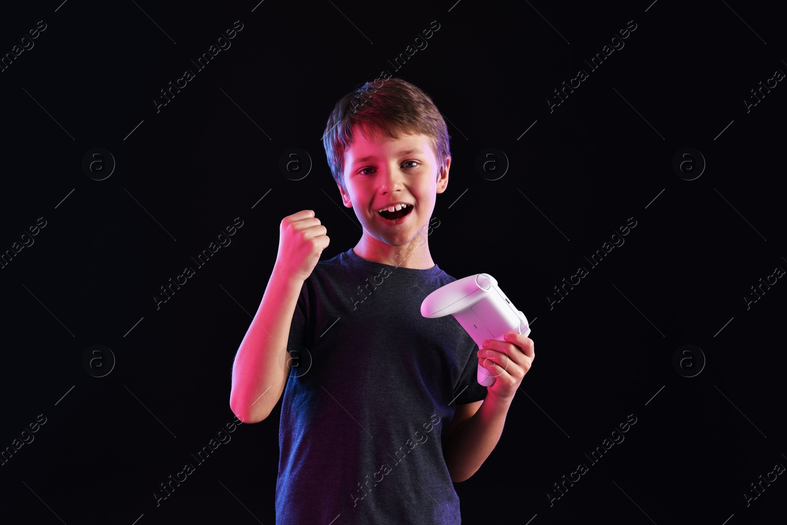 Photo of Happy little boy with controller on black background