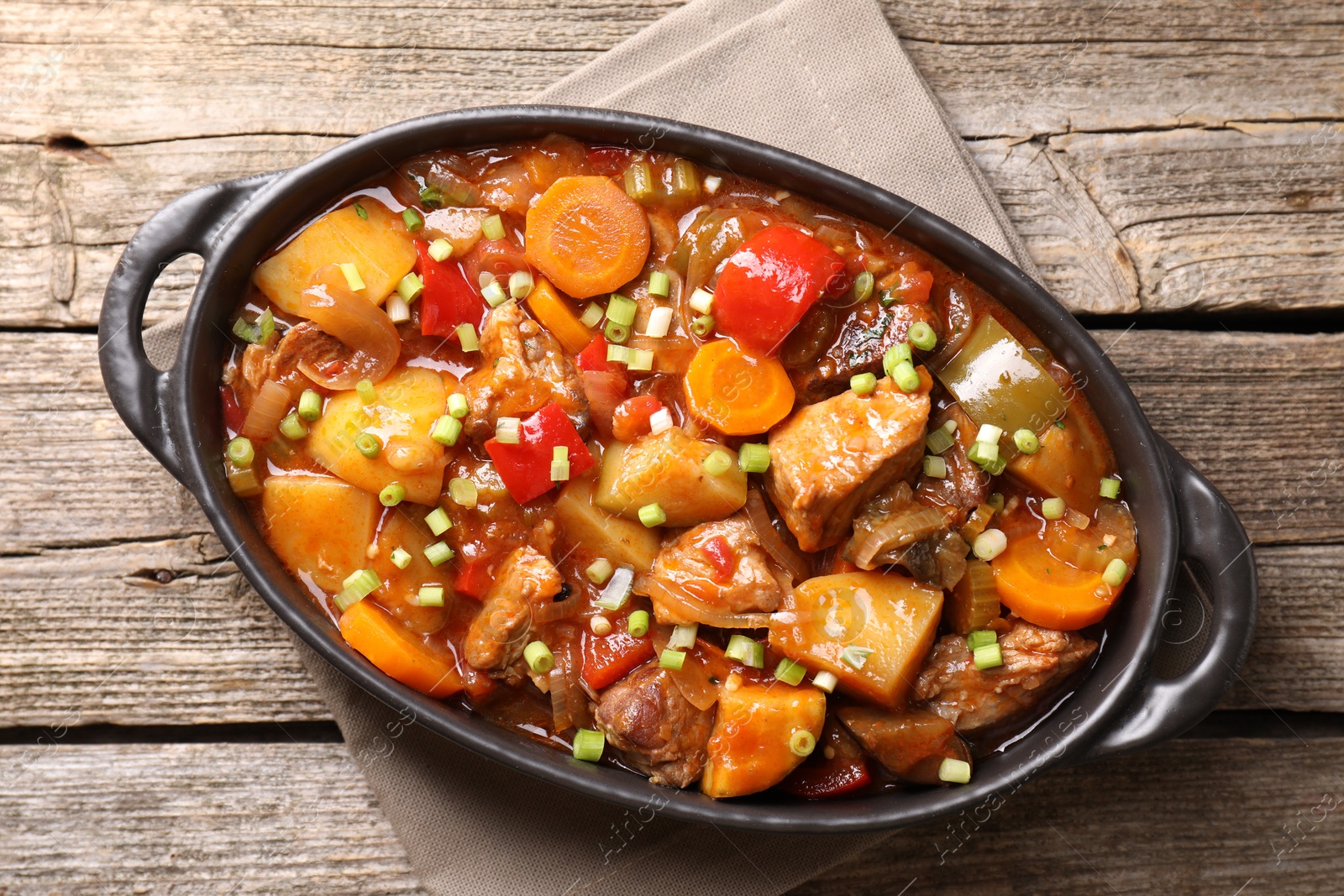 Photo of Delicious stew with vegetables in baking dish on wooden table, top view